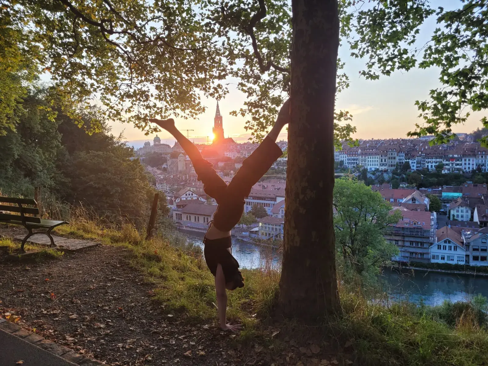 Dafna doing a yoga handstand on a hill in front of a European city