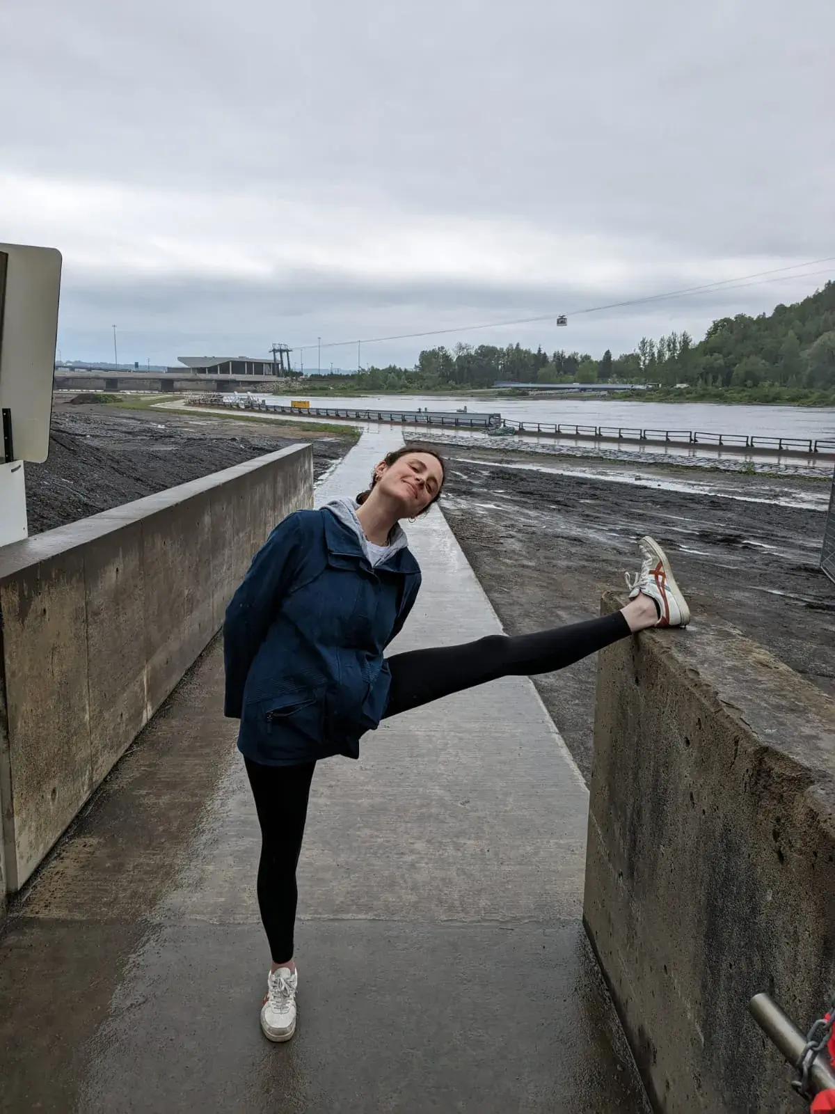 Dafna doing a yoga stretch on a fence near a waterfall