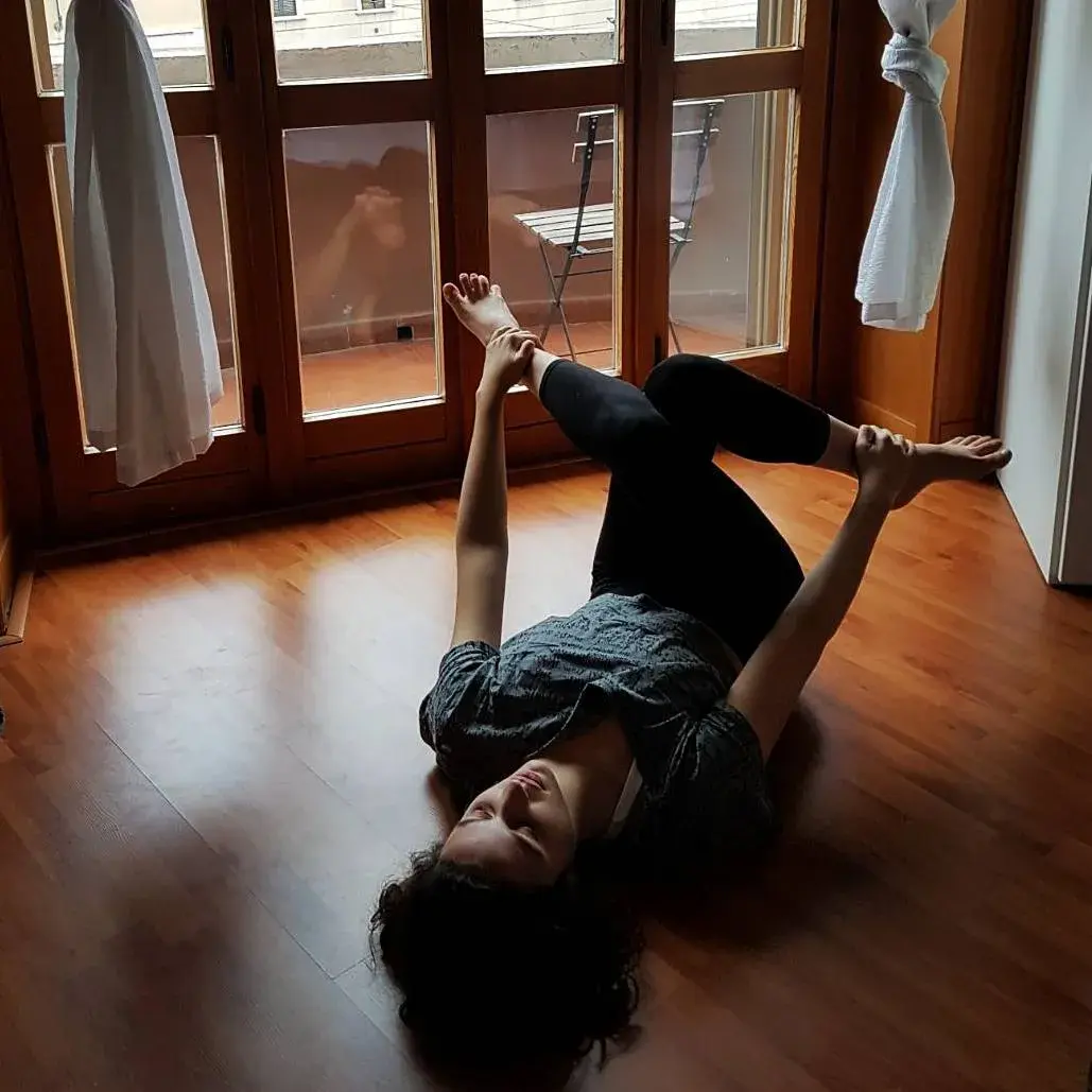 Dafna doing yoga stretches on a wooden floor